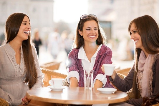 Three young women drinking coffee in a cafe.