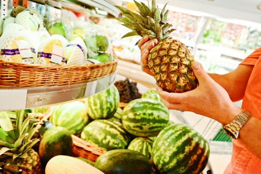 Man choosing pineapple in grocery store